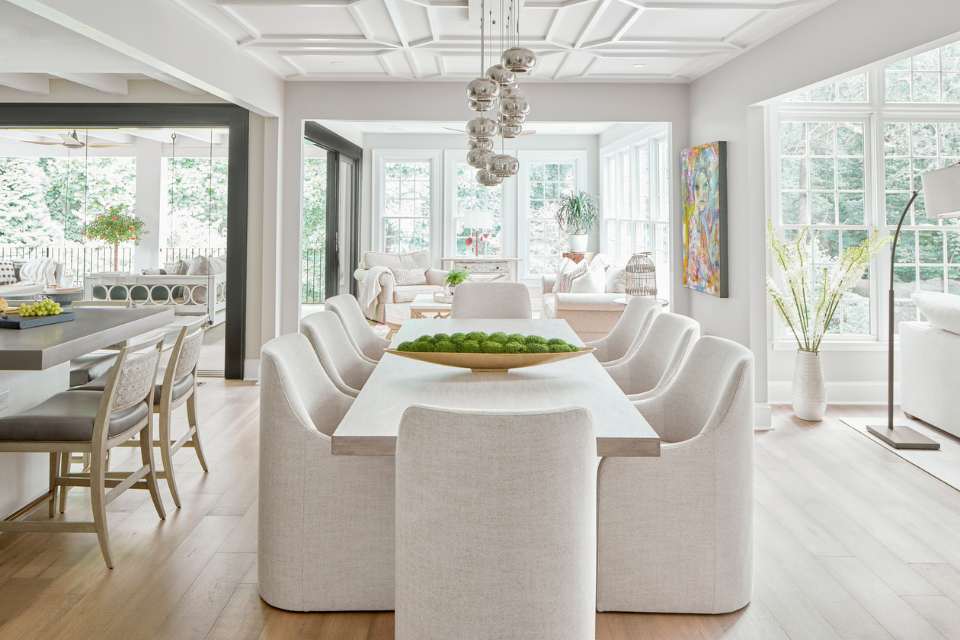 open concept designer home with white dining room seating, statement lighting, and large pocket doors to porch